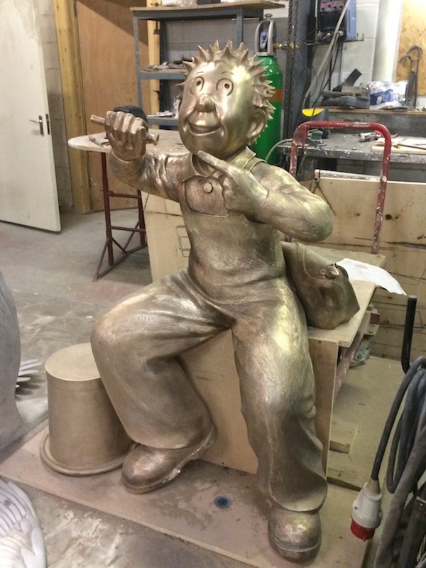 Golden unfinished bronze figure of a seated character in the workshop