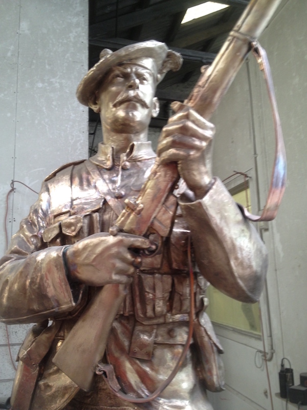 Bright bronze statue of a standing soldier in the workshop