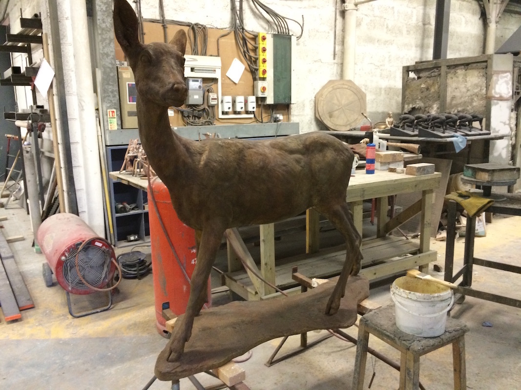 Deer sculpture standing amid tools and equipment in the foundry workshop