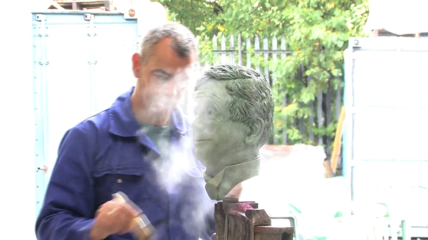 Craftsperson applying patina to bronze