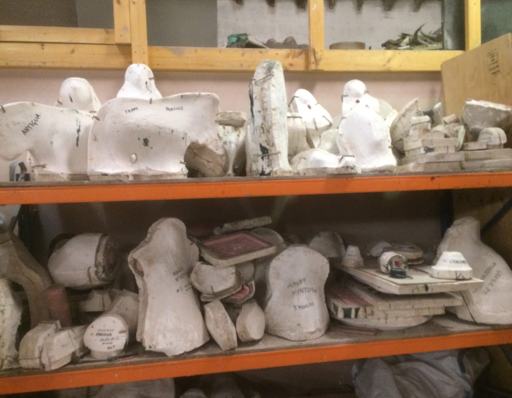 Shelves containing many white plaster moulds and mould sections in a foundry